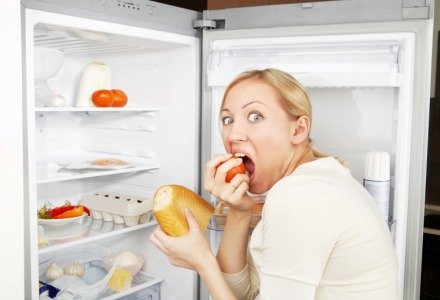 γυναίκα τρώει λαίμαργα μπροστά στο ψυγείο